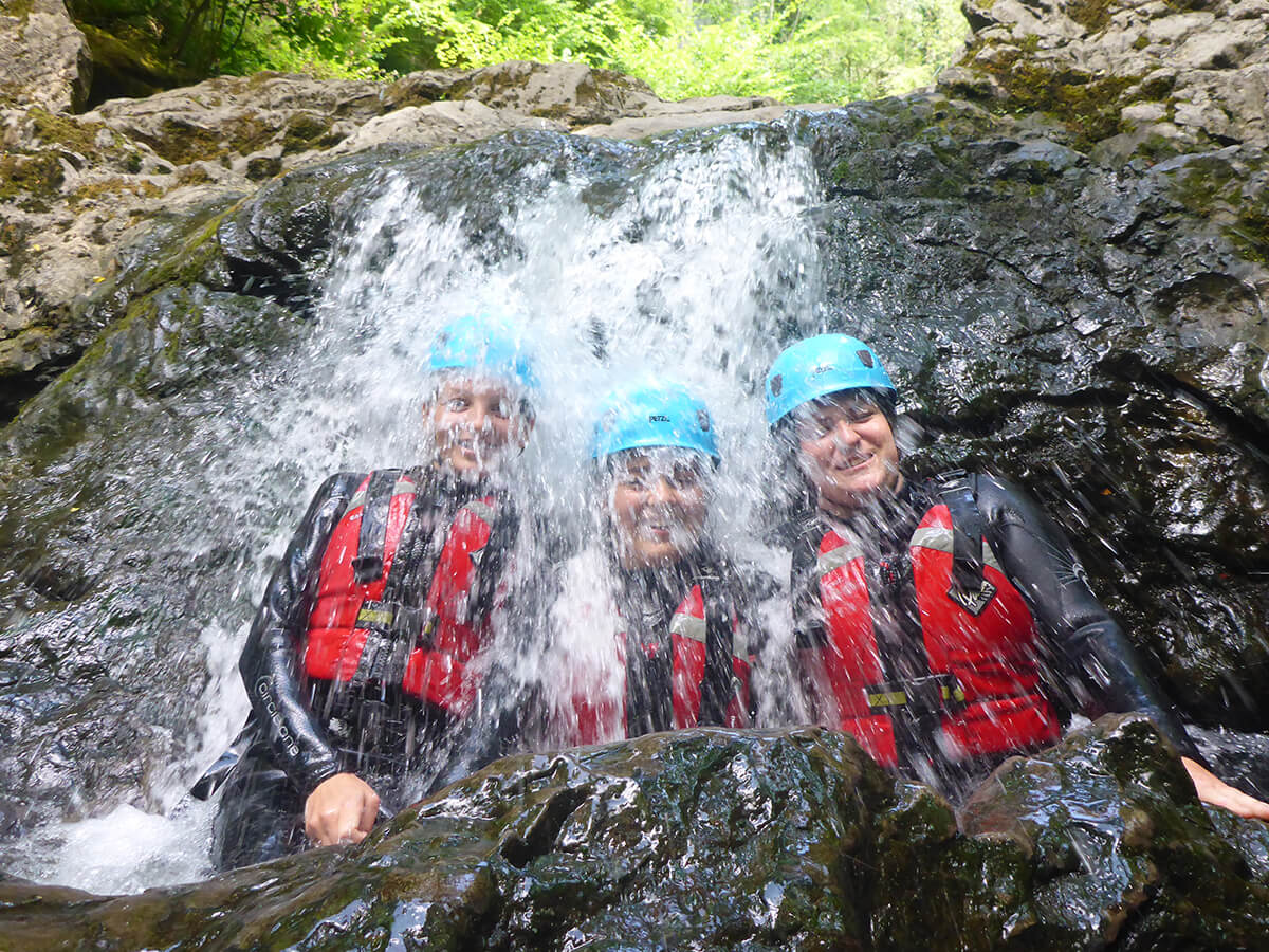Three people under a waterfall