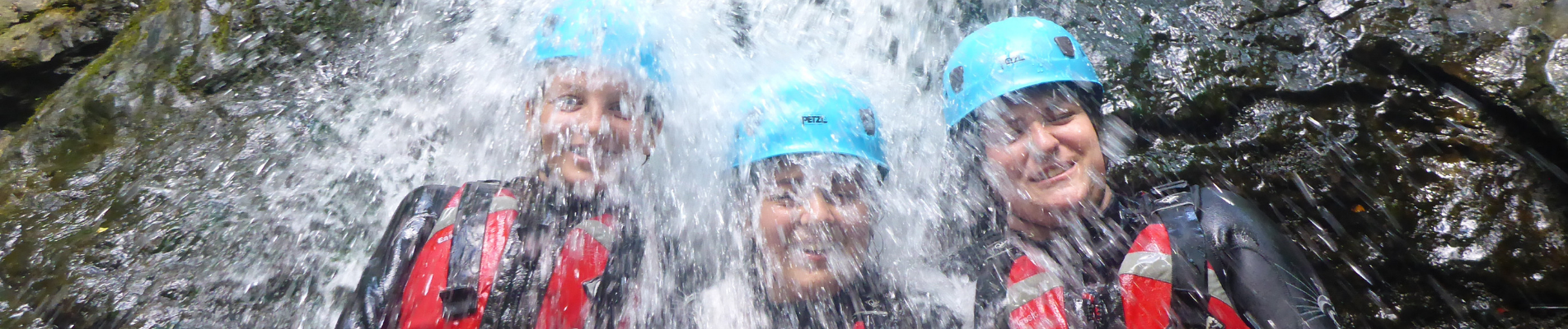 Three people under a waterfall