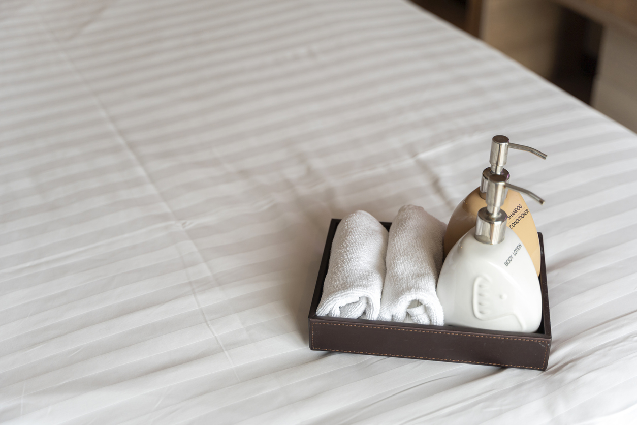 White towel shampoo and soap on a bed. Hotel towel and shampoo and soap bath bottle set on white bed decorated